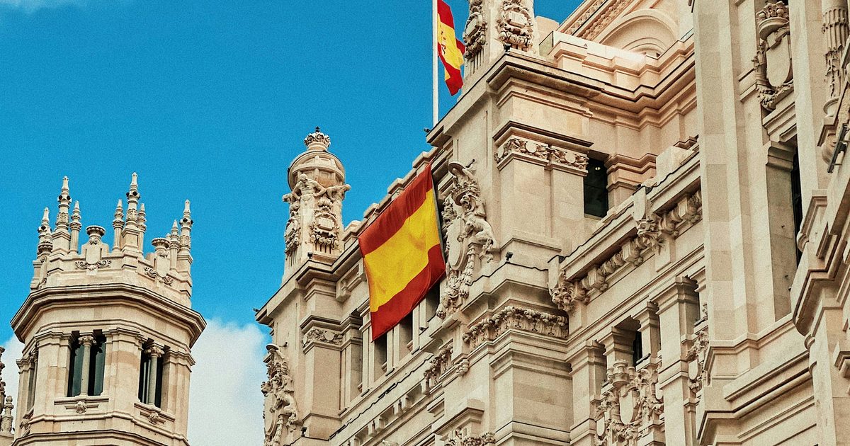 Fachada del Palacio de Cibeles en Madrid con la bandera de España y cielo azul
